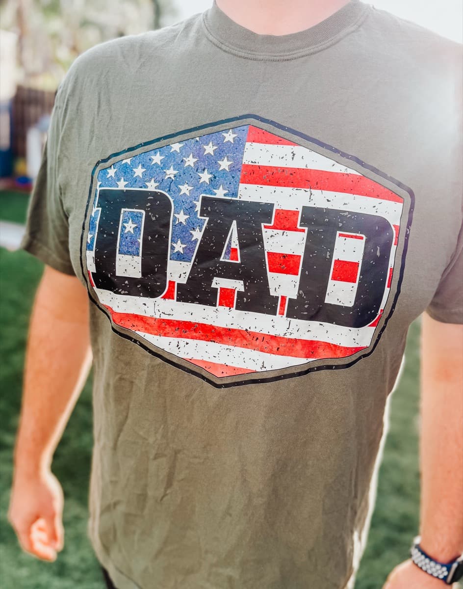 Olive green tee with a distressed DAD and American flag DTF print, worn outdoors