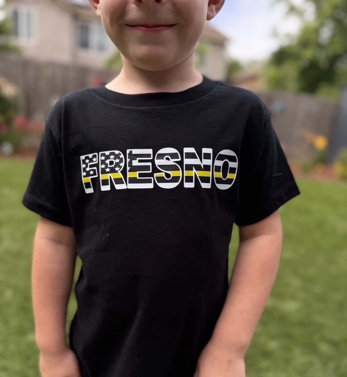 Black tee with FRESNO thin yellow line DTF print worn by a child outdoors
